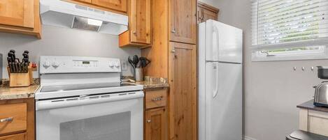 A kitchen with wooden cabinets, a white stove, and a refrigerator.