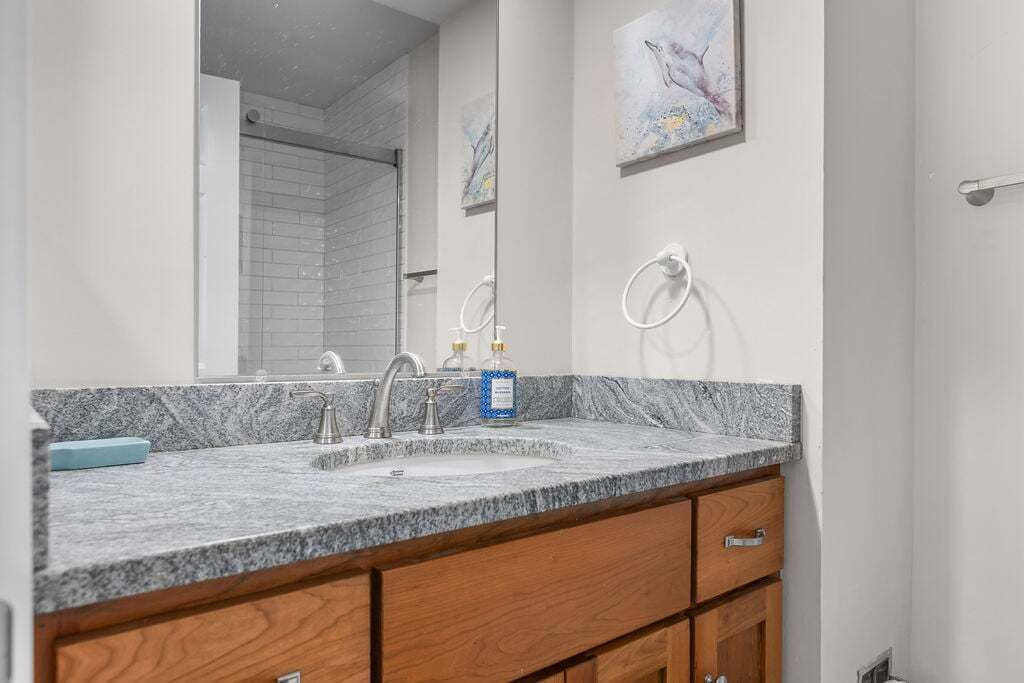 Une salle de bain avec un comptoir en granit, un lavabo et des armoires en bois.