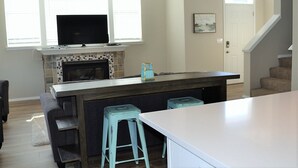 Une cuisine avec une cheminée, des tabourets de bar et un escalier.