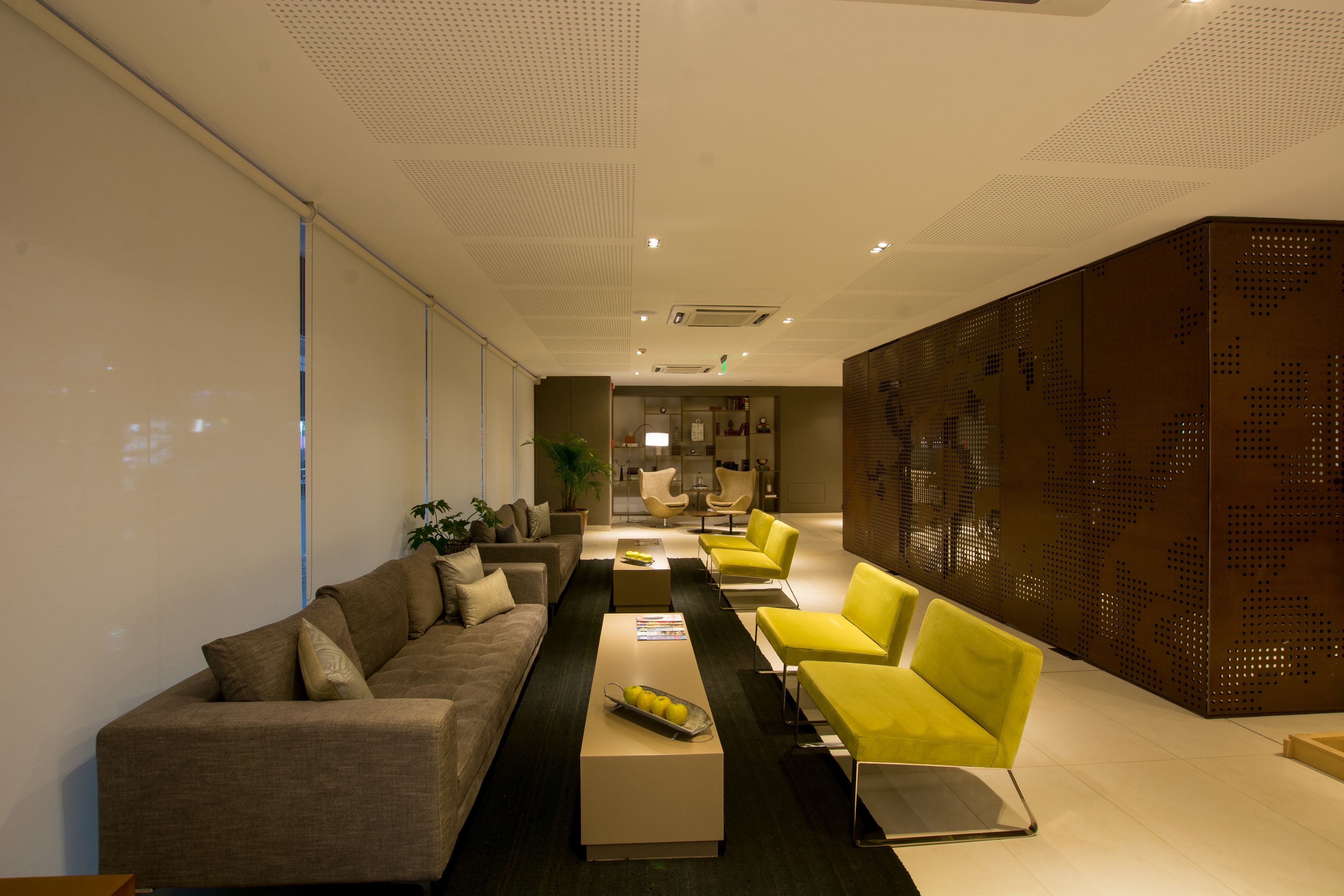 A modern waiting area with a sofa, yellow chairs, and a coffee table.