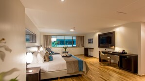 A modern hotel room with a bed, bedside table, lamp, TV, desk, and a view of the outdoors. - Caseros 248 Hotel (Córdoba)