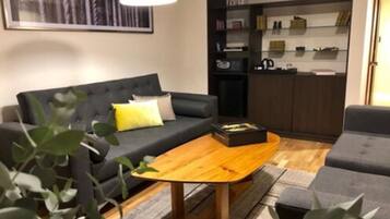Un salon moderne avec un canapé gris foncé, une table basse en bois et une petite plante.