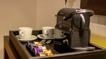 A tray with two white cups and a coffee maker, along with colorful pens and a spoon.