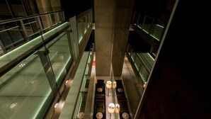 An interior view of a modern building with glass railings and a central column. - Caseros 248 Hotel (Córdoba)