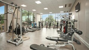 A gym with various exercise equipment, large windows, and a flat-screen TV on the wall. - Sandton Skye Suite 604 (Sandton)