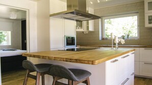 Una cocina moderna con una isla de madera, taburetes de bar y un horno empotrado.