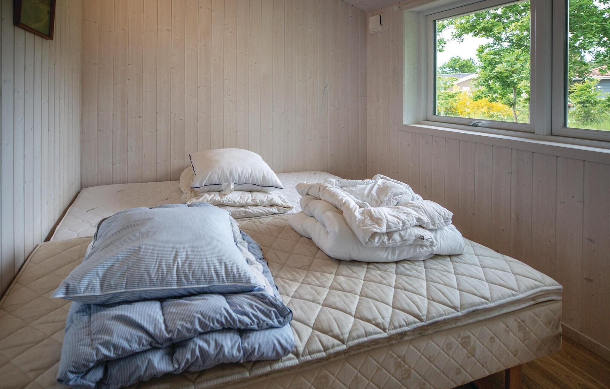 A single bed with a quilted mattress, two pillows, and a folded blanket.