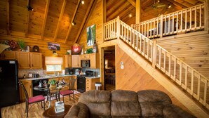 A cozy cabin interior with a wooden staircase, a dining area with a table and chairs, and a living room with a sofa. - ✧ Majestic Cabin - KING bed - NO CLEANING FEE! (Dryfork)