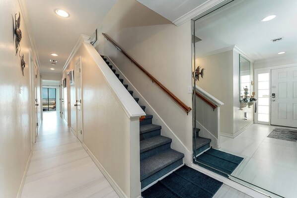 A hallway with a staircase leading to a mirrored room.