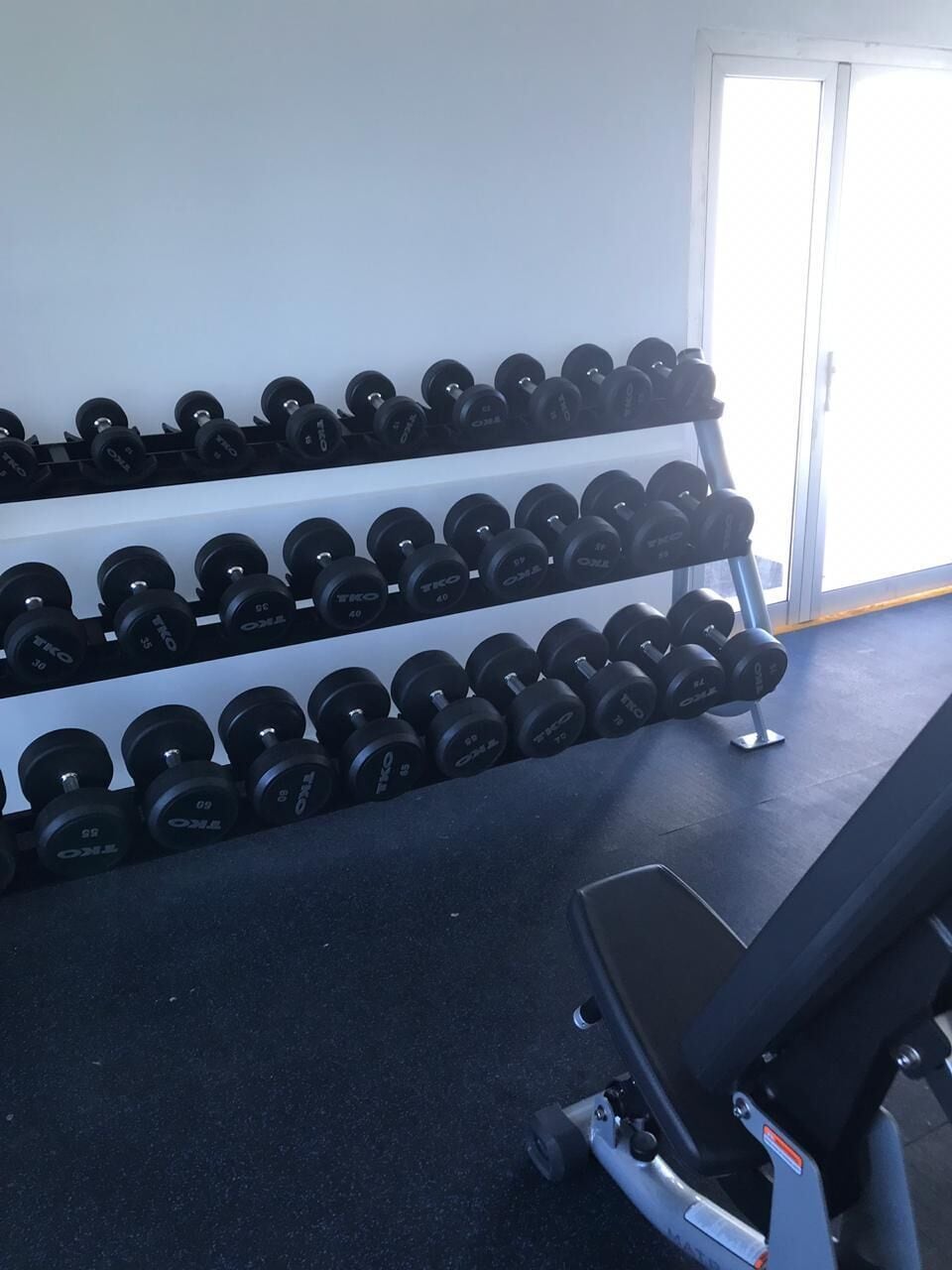 A gym with a rack of dumbbells and a stationary bike.