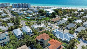 A coastal residential area with beachfront properties, including houses with red-tiled roofs and a large hotel complex. - Crow's Nest Spinnakers Cottages: 250 Steps to Beach! Pool! (Holmes Beach)