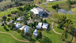 An aerial view of a residential area with multiple houses, a large barn, and a pond. - PINNACLE VALLEY Chalet 11 SHERPA'S REST (Merrijig)