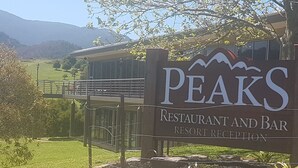 A sign for Peaks Restaurant and Bar with a view of a mountain and a bridge in the background. - PINNACLE VALLEY Chalet 11 SHERPA'S REST (Merrijig)