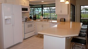 A kitchen with white cabinets, a refrigerator, an oven, a sink, and a large island with bar stools. - Beautiful Water Views, 7-min Walk to Tigertail Beach entrance, 5 bikes, Hot Tub (Marco Island)