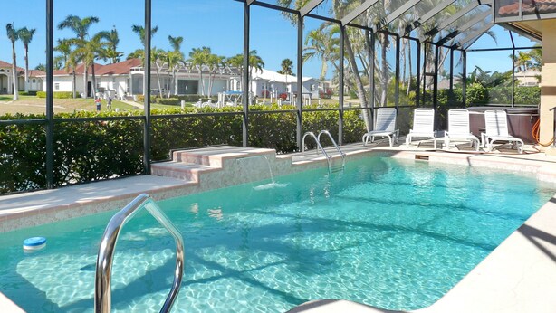 A pool area with clear water, a pool ladder, and lounge chairs. - Beautiful Water Views, 7-min Walk to Tigertail Beach entrance, 5 bikes, Hot Tub (Marco Island)