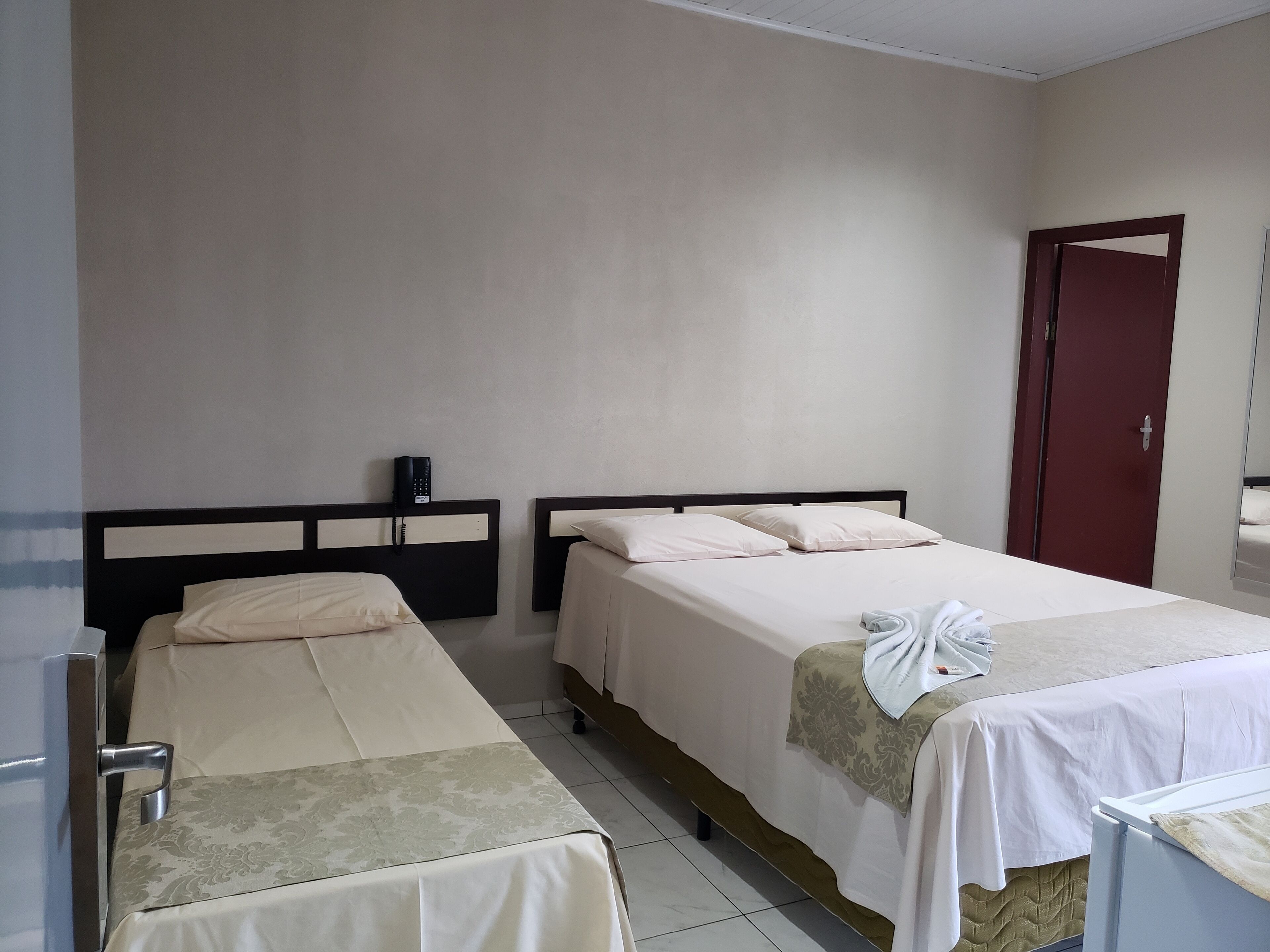 Habitació d'hotel amb dos llits, una porta vermella i un telèfon a la paret.