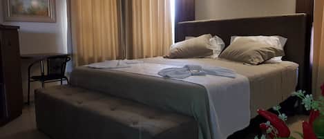 A neatly arranged bedroom with a bed, a bedside table, a chair, and a small table.