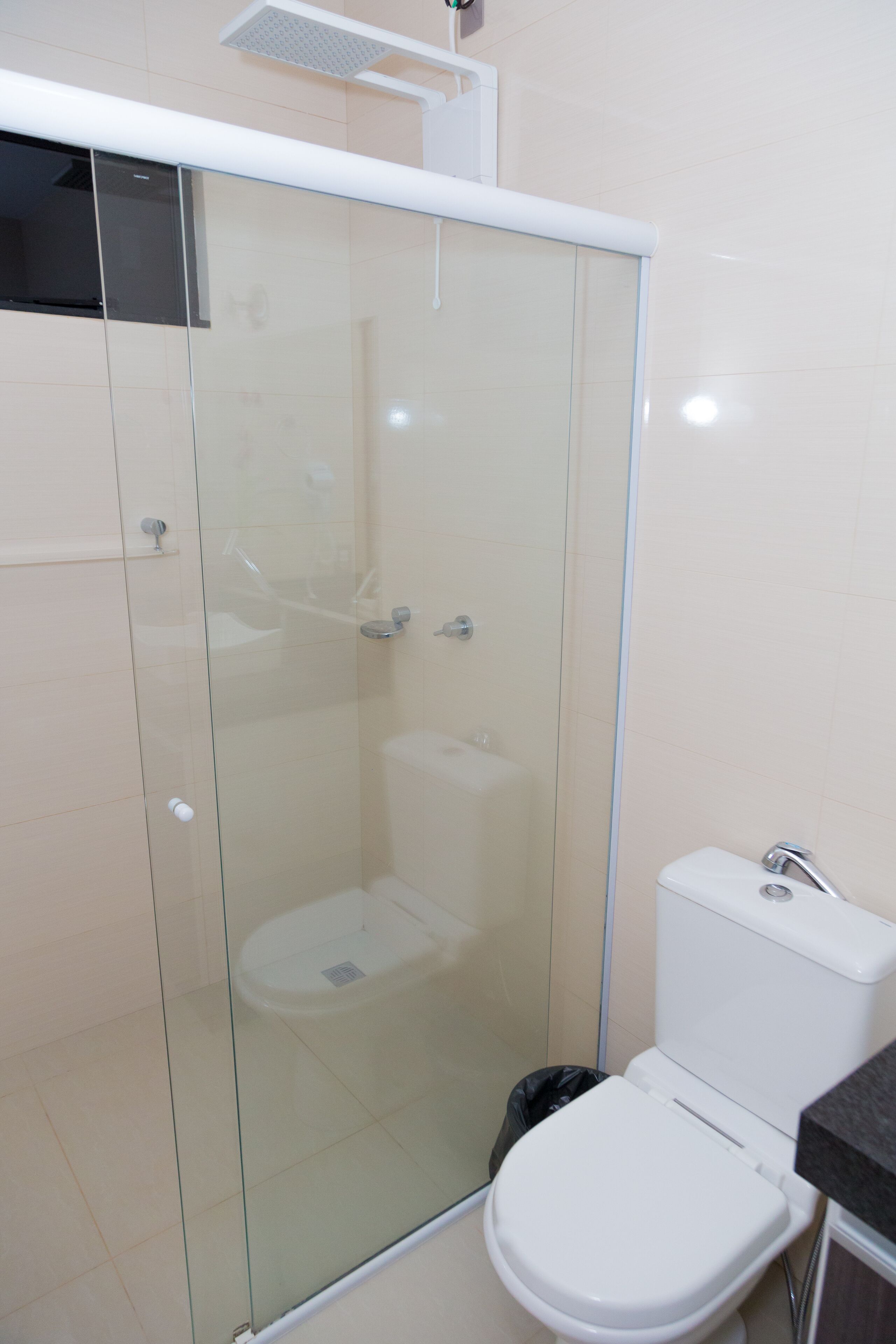 Un baño con ducha de vidrio, inodoro blanco y lavamanos.