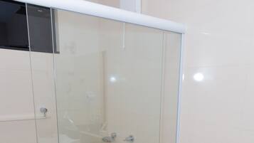 Un baño con ducha de vidrio, inodoro blanco y lavamanos.
