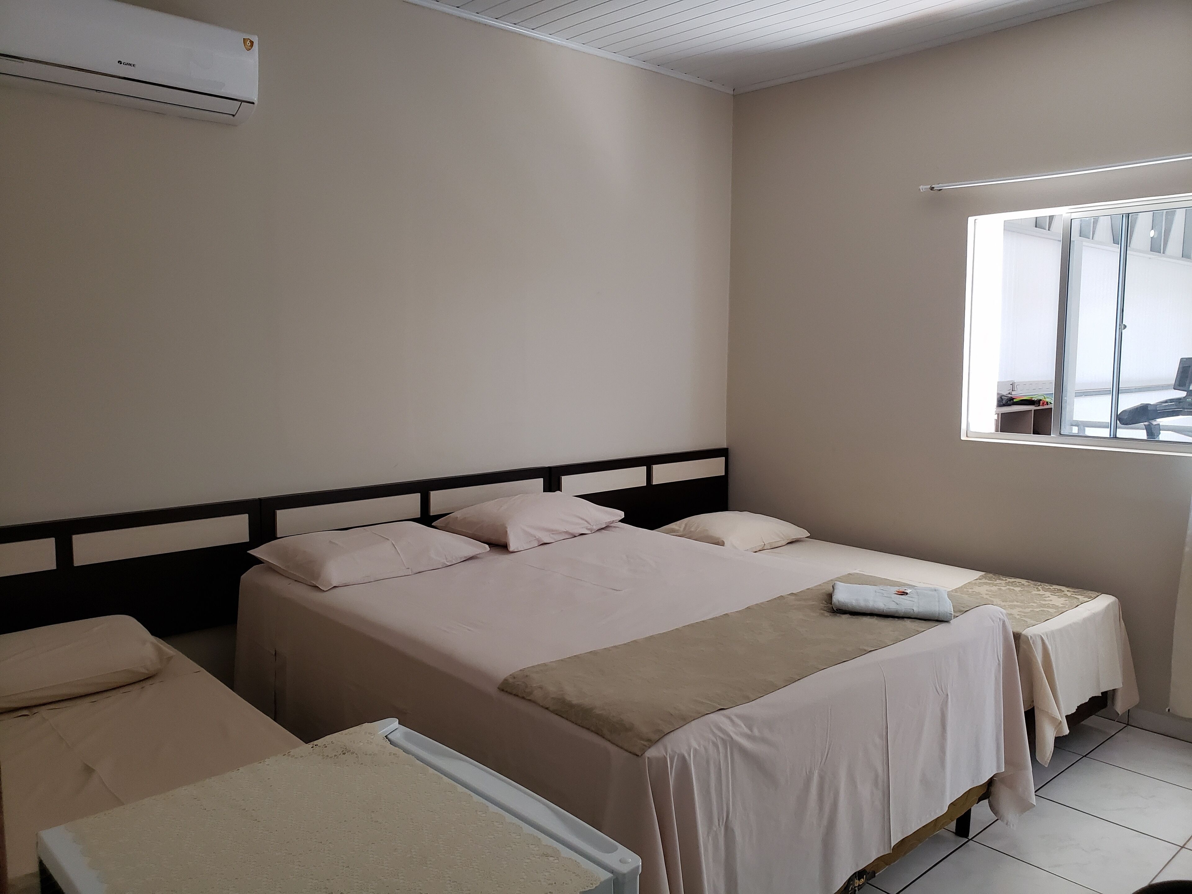 Quarto de hotel com duas camas, uma janela e um ventilador de teto.