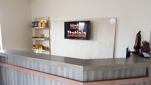 En hotellreception med en digital skärm som visar texten ”Hotel Italiaia”.