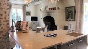A kitchen with a large island, a fireplace, and a chandelier. - Mas in Eygalières with Heated Pool (Eygalières)