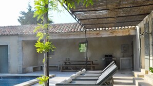 A poolside area with lounge chairs, a picnic table, and a barbecue grill. - Mas in Eygalières with Heated Pool (Eygalières)
