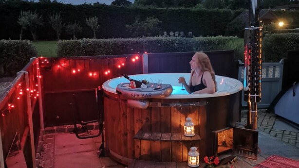An outdoor hot tub area with a spa bar, surrounded by string lights and decorative lanterns. - Oak Cottage: A Breathtaking Barn Retreat with a Private Log-Fired Hot Tub (maidstone)