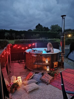 Een buitengebied met een hottub en een spa-bar, omringd door lichtslingers en decoratieve lantaarns.