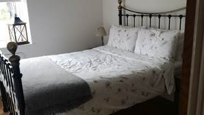A single bed with a floral bedspread, a bedside lamp, and a striped rug on a wooden floor. - Oak Cottage: A Breathtaking Barn Retreat with a Private Log-Fired Hot Tub (maidstone)