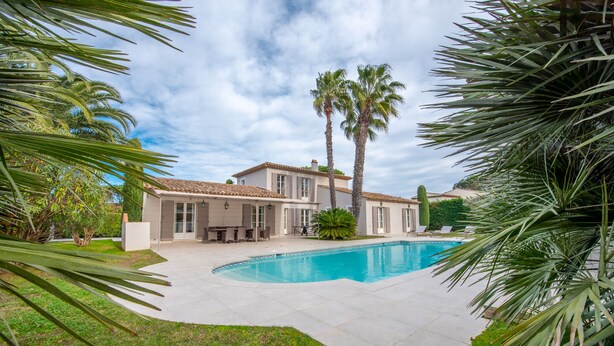 A large house with a swimming pool, surrounded by palm trees and a well-maintained lawn. - Villa Saint-Tropez (Gassin)