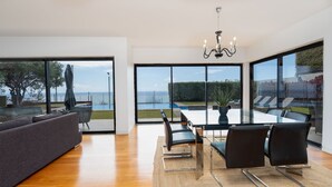 A modern dining area with a view of the sea, a chandelier, and a large window. - Villa Vitória by LovelyStay (Funchal)