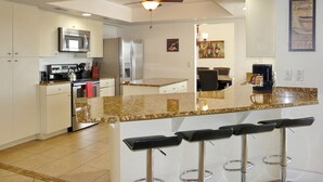 Cozinha moderna com ilha central, eletrodomésticos de aço inoxidável e ventilador de teto.