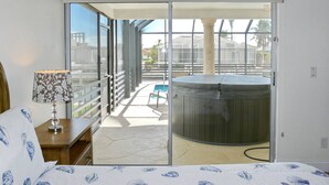 Quarto com uma grande porta de vidro deslizante que dá para uma varanda com hidromassagem e piscina.