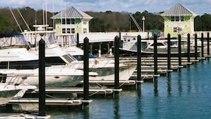 A marina with boats docked at wooden piers, two small green-roofed structures, and a clear sky. - Sisters 3 by the Sea, 400 Feet To The Beach (Cape Charles)