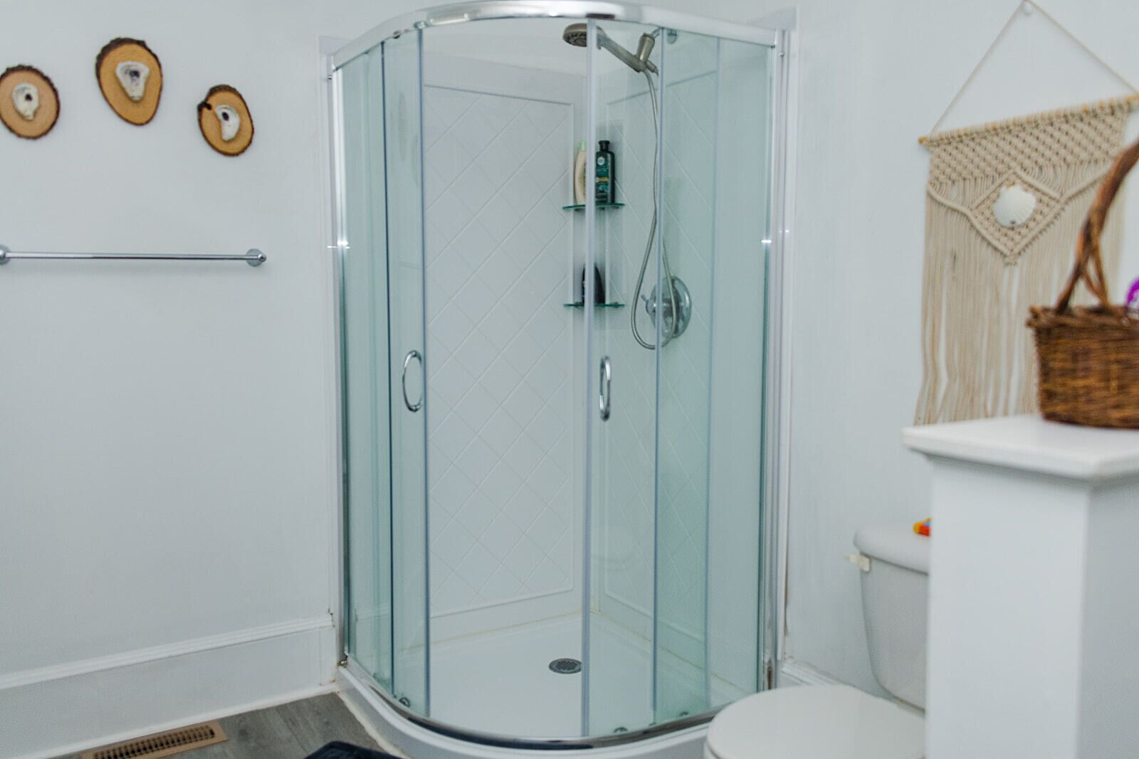 A modern bathroom with a glass-enclosed shower, a toilet, and a towel rack.