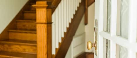 A wooden staircase with white railings and a door with a round knob.