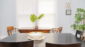 A dining area with a dark wooden table, two chairs, a vase with green leaves, and a framed picture on the wall. - Sisters 3 by the Sea, 400 Feet To The Beach (Cape Charles)