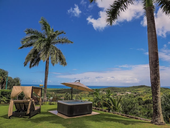 A hot tub, a covered seating area, and a view of the ocean.