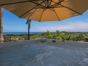 A hot tub with a view of the ocean and hills.