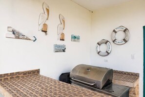 A barbecue area with a grill, wall decorations including life rings, and a sign that says 'Pisantus.'