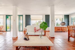 A spacious living area with a white sofa, a coffee table, and a decorative plant.