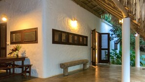 A covered outdoor area with a bench, a table, and a wall-mounted light fixture. - La Cueva Eco-Lodge (Las Galeras)