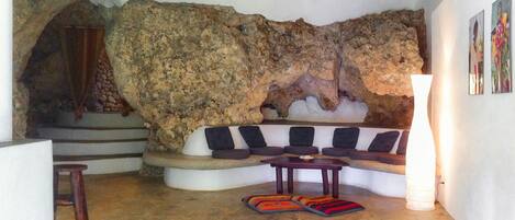 A living room with a stone wall, a curved sofa, a small table, and a stool.