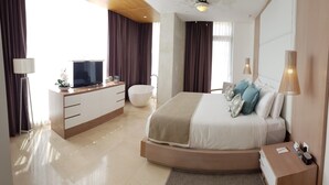 Ein modernes Hotelzimmer mit einem gewölbten Bett, einem Nachttisch, einem Fernseher, einem großen Fenster und einem Badezimmer mit einer Badewanne.