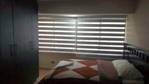 A bedroom with a bed, a wardrobe, and a window with blinds. - Portal Rent Apart 6 (Cochabamba)