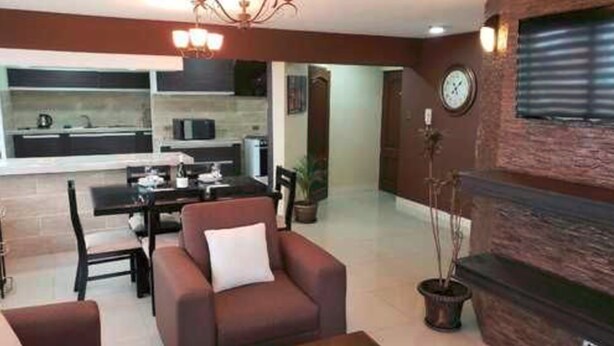 A modern living room with a fireplace, a dining area, and a kitchen in the background. - Portal Rent Apart 6 (Cochabamba)