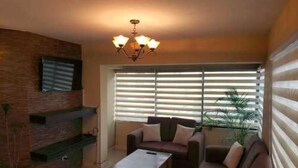 A living room with a fireplace, a sofa set, a coffee table, and a chandelier. - Portal Rent Apart 6 (Cochabamba)