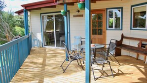 Eine Holzterrasse mit Tisch, Stühlen und einer Bank, sowie eine Schiebetür zu einem Innenbereich.
