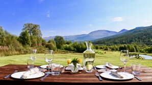 Une table en bois dressée pour un repas, avec une vue imprenable sur les montagnes et le lac.